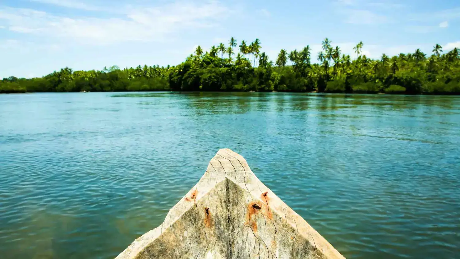 wooden canoe, facing lush island, calm water, tropical scenery, peaceful moment