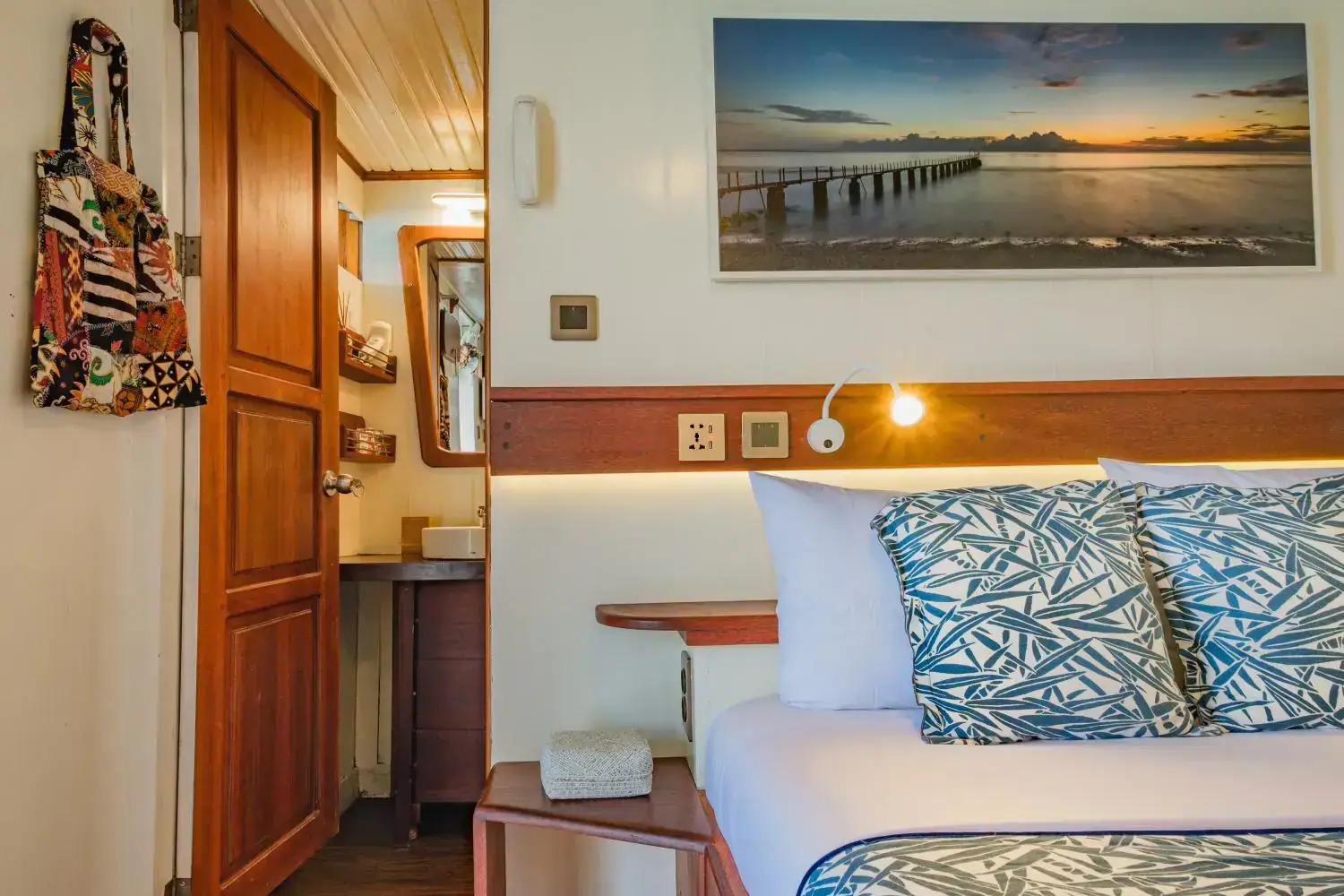 sea view cabin details, bedside table, enter the private bathroom, wooden door, painting above the bed 